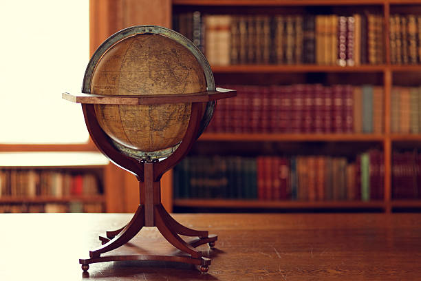 Library interior "Library interior: Desk with globe, defocused background with bookshelvesSimilar images:" desktop globe stock pictures, royalty-free photos & images