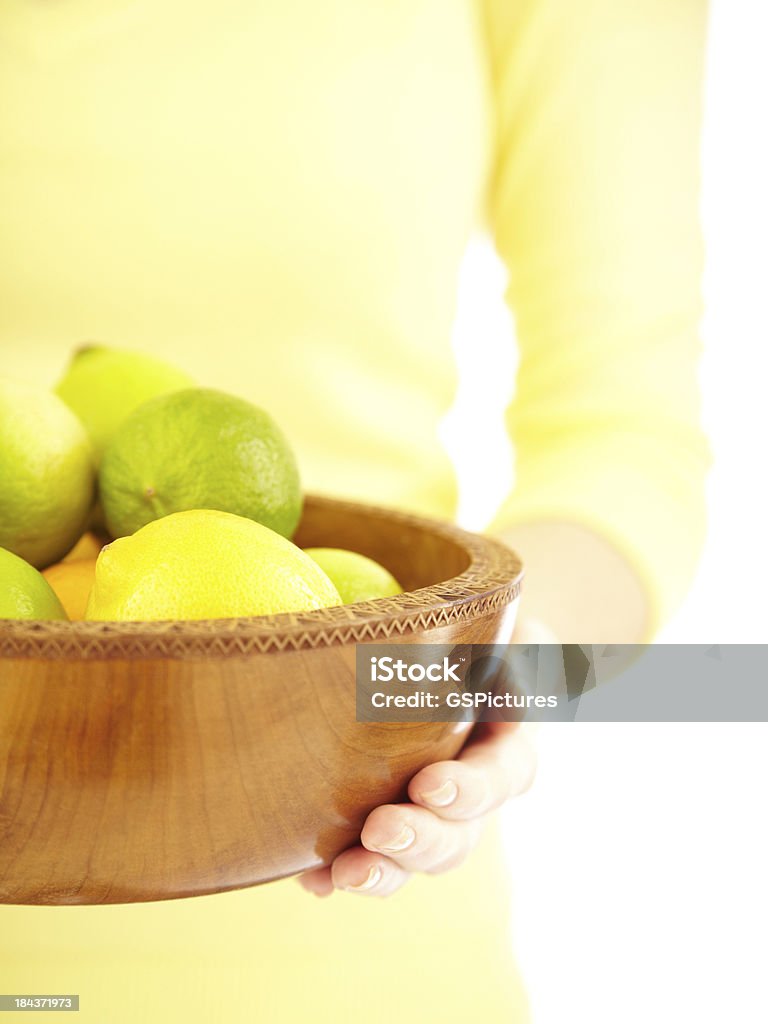 Donna con una ciotola di legno di lemons limes e - Foto stock royalty-free di 20-24 anni