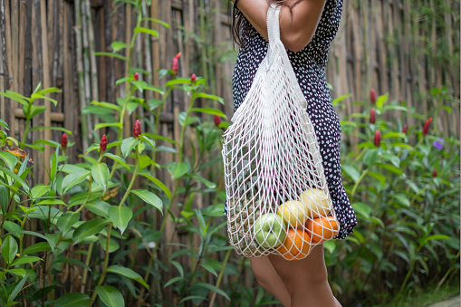 Close-up shot of Unrecognizable Woman Carrying Groceries On Reusable Net Shopping Bag