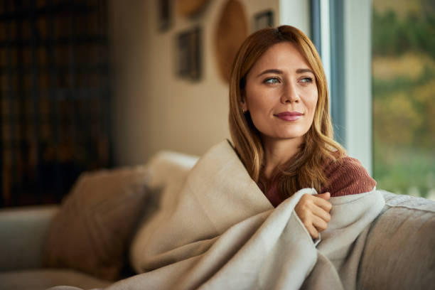 istock A pretty woman sitting on the sofa, wrapped in a blanket. 1843729385