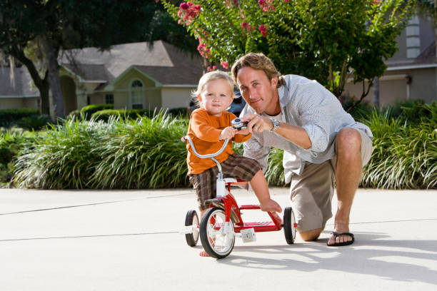 istock Father helping toddler ride tricycle 184374550