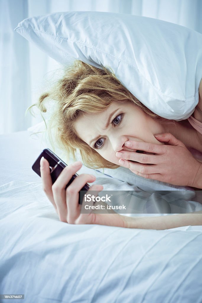 Bad news Shocked young adult woman reading bad news on her cell phone. Surprise Stock Photo