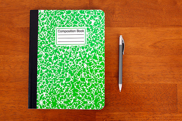 Composition Book Writing composition book with an ink pen on a wooden desk top.Please also see my Education Related lightbox: composition stock pictures, royalty-free photos & images