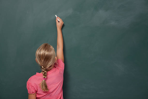 vue arrière de petite fille écrit sur le tableau noir vide - blackboard child thinking little girls photos et images de collection