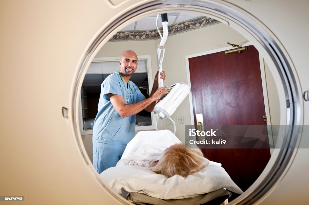 Healthcare worker preparing patient for CT scan Healthcare worker, 40s, with female patient, 50s, preparing for CT scan. Male Nurse Stock Photo