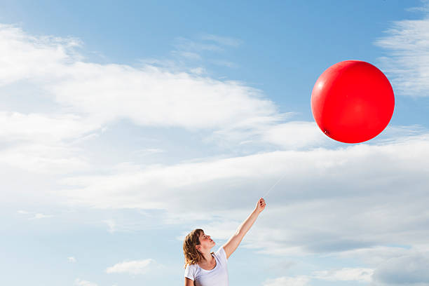 istock Young woman holding a red balloon 184376877