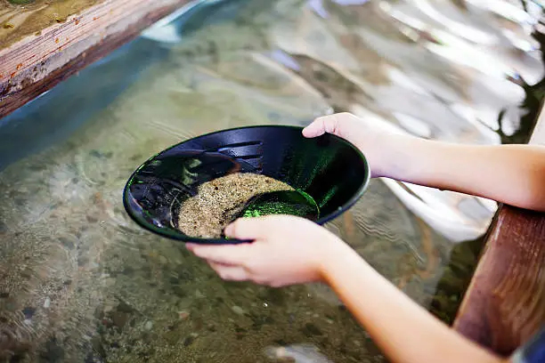 "Child panning for gold in historical Coloma, place that initiated 1849 Gold Rush in California."