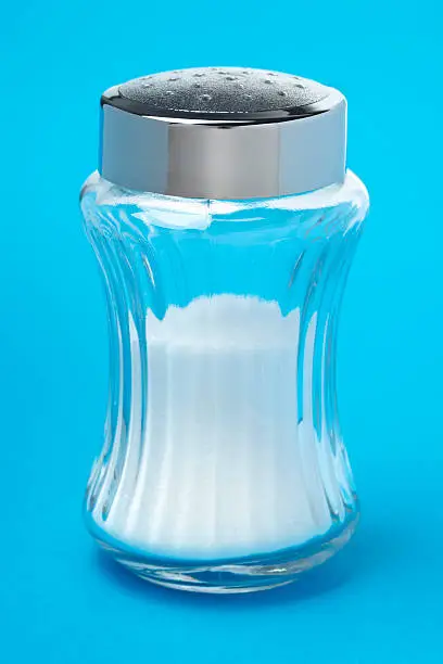 Glass saltshaker on blue background