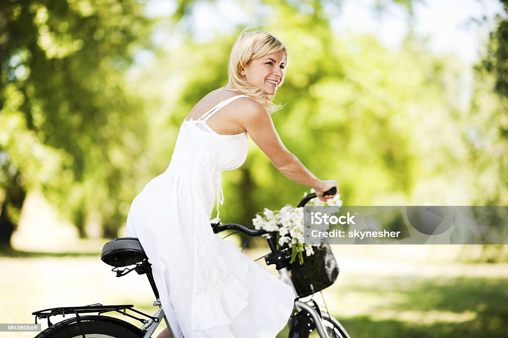 Vista lateral de una hermosa mujer montando en bicicleta. - Foto de stock de Actividad libre de derechos