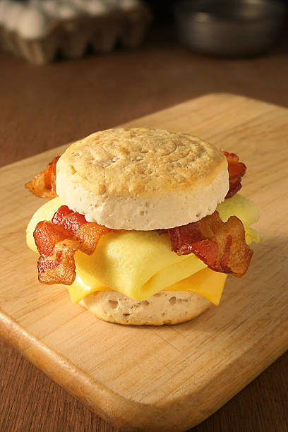 Breakfast Sandwich "Breakfast sandwich of scrambled eggs, crispy bacon and melted cheese on a freshly baked buttermilk biscuit." biscuit quick bread photos stock pictures, royalty-free photos & images