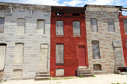 A street of abandoned and boarded up rowhouses in a blighted part of the city.