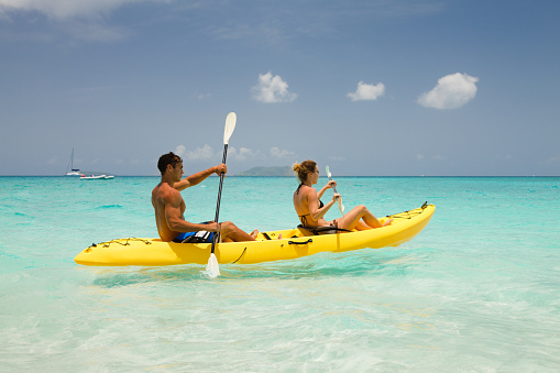 young couple kayaking through the Caribbean crystal clear waters