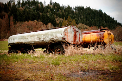 Two abandoned oil tankers left in a field to rust. Vignette added.