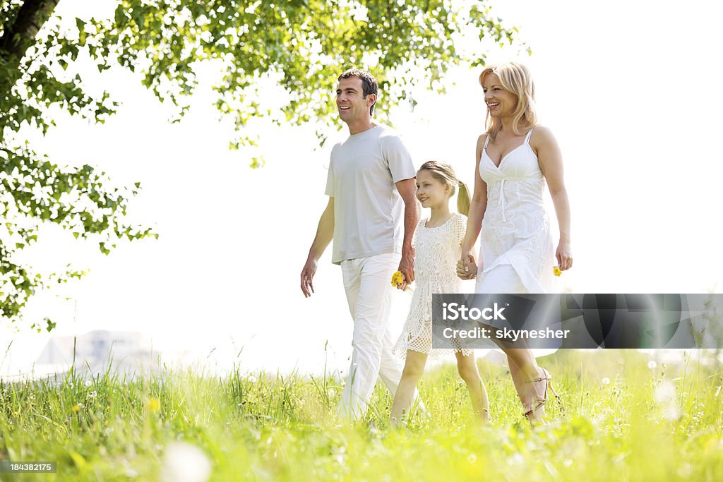 Padres con una hija caminando en un parque. - Foto de stock de Andar libre de derechos