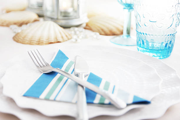 istock Place setting with shells blue striped napkin on scalloped dishes 184382469