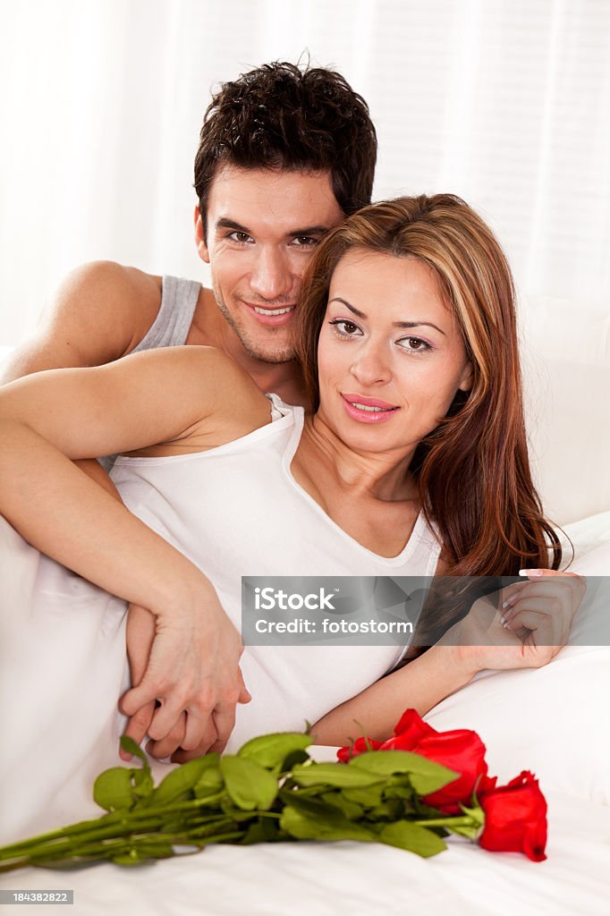 Giovane coppia con rose rosse a letto - Foto stock royalty-free di 20-24 anni