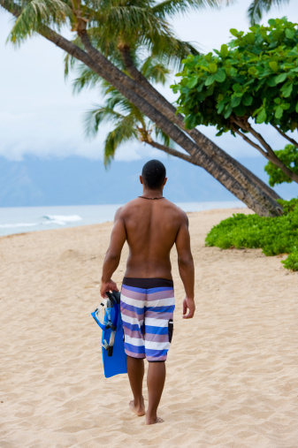 An African American man walking down the beach in Hawaii