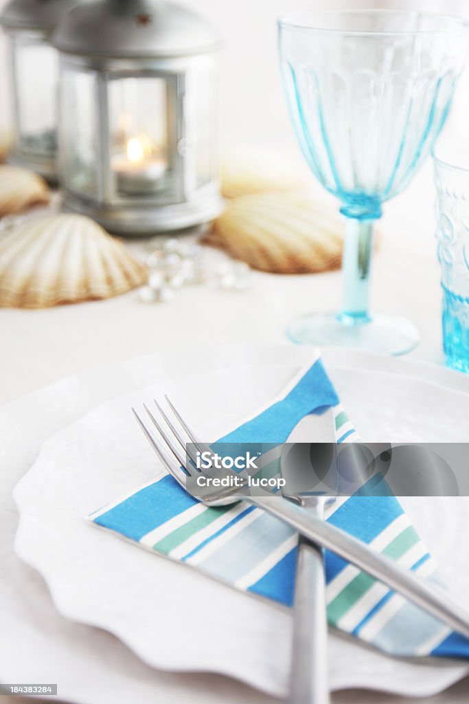 Table dressée avec des serviettes rayé bleu sur plats festonnée - Photo de Blanc libre de droits