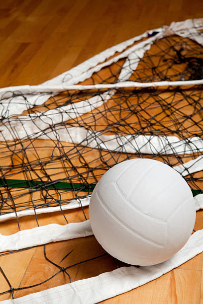 A volleyball and net on the gym floor stock photo