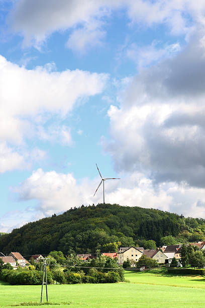 istock Single wind turbine on hill above small village 184384939