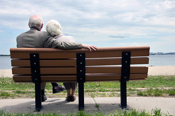 пожилая пара, сидя на парк скамейка - couple loving urban scene selective focus стоковые фото и изображения