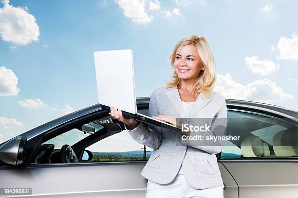Donna Sorridente Utilizzando Il Proprio Computer Portatile Contro Il Cielo E Cloud - Fotografie stock e altre immagini di Automobile