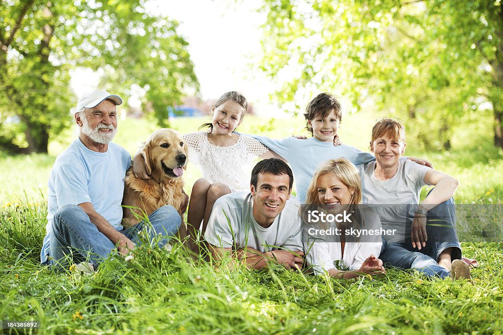 Duże rodziny Z dziadkami siedzi w trawie. - Zbiór zdjęć royalty-free (Pies)