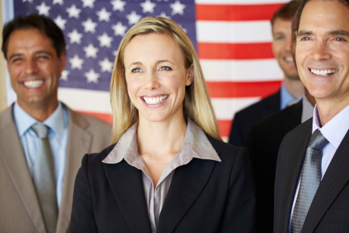 Portrait of confident business associates smiling with flag in the background