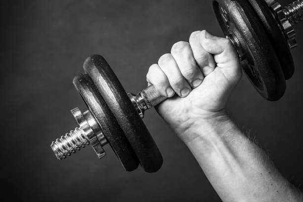 istock Man`s hand holding weight. Body building in studio, black and white. 1843862572