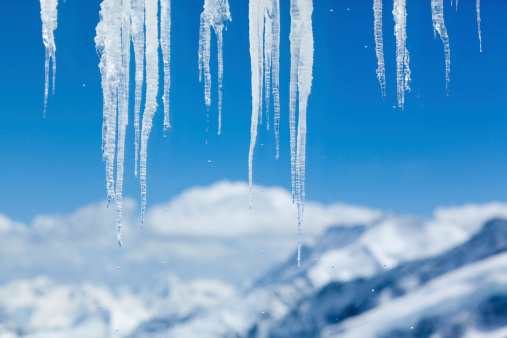 Icicles with mountain peaks in the background.