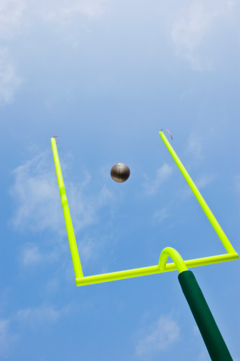 Field Goal or Extra Point in American Football looking up at the goal post as the ball flies through the air in motion