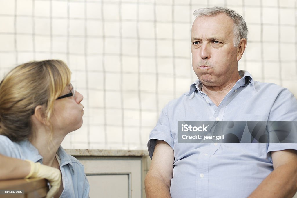 Healthcare worker checking man's swallowing power "Healthcare worker. wearing surgical gloves, checking man's facial muscles and lip strength by getting him to puff out his cheeks.  She is a Speech Therapist specialising in dysphagia (swallowing) . Neutral tiled background could be in a hospital or could be a home visitMore like this" Speech Therapy Stock Photo