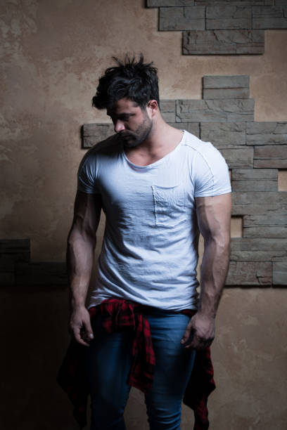 Cool Fashion Man in Blue Jeans Standing and Looking Away - Against Brick Wall on Copy Space