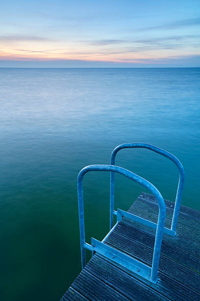 Steps from the side of a jetty into a big lake. Photographed at dawn.