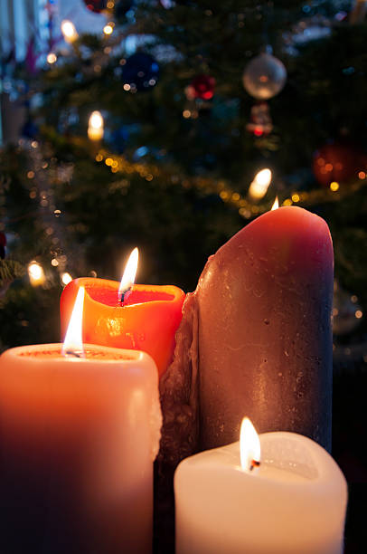 istock Four burning candles with cristmas tree in background 184387630
