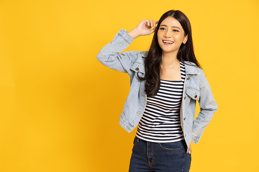 Portrait of Happy Asian woman in jacket jeans smiling isolated on yellow background