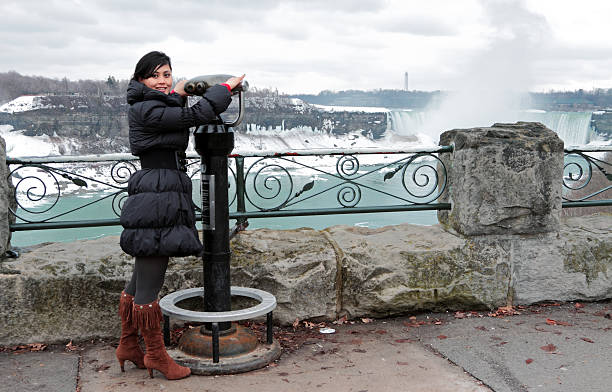 Beautiful female tourist getting excited in front of Niagara Falls in winter