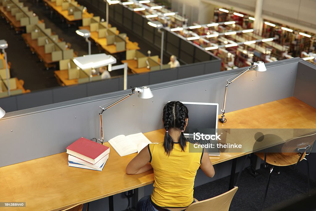 Femmina studente nella biblioteca universitaria - Foto stock royalty-free di Studente universitario