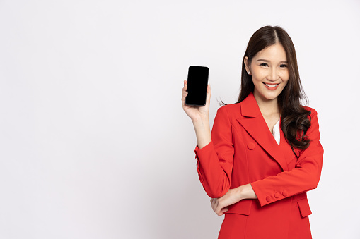 Portrait of Asian business woman in red showing or presenting mobile phone application isolated over white background, Asia Thai model