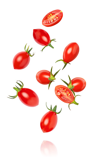 Fresh red cherry tomatoes with half sliced falling isolated on white background