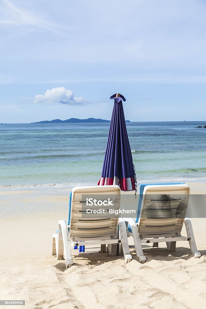 chair on beach Rear view of a couple sitting on deck chairs enjoying vacation Beach Stock Photo