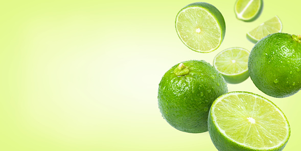 Lime with cut half slice flying in the air isolated on green color background. Copy space for text.