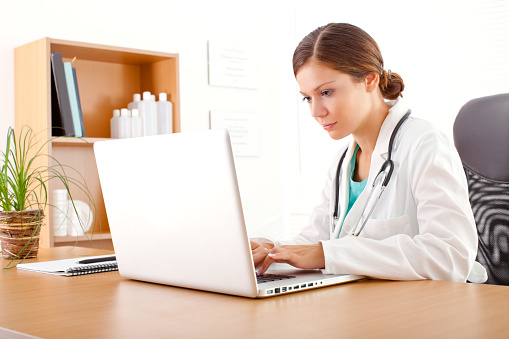 Young nurse working in office on laptop.