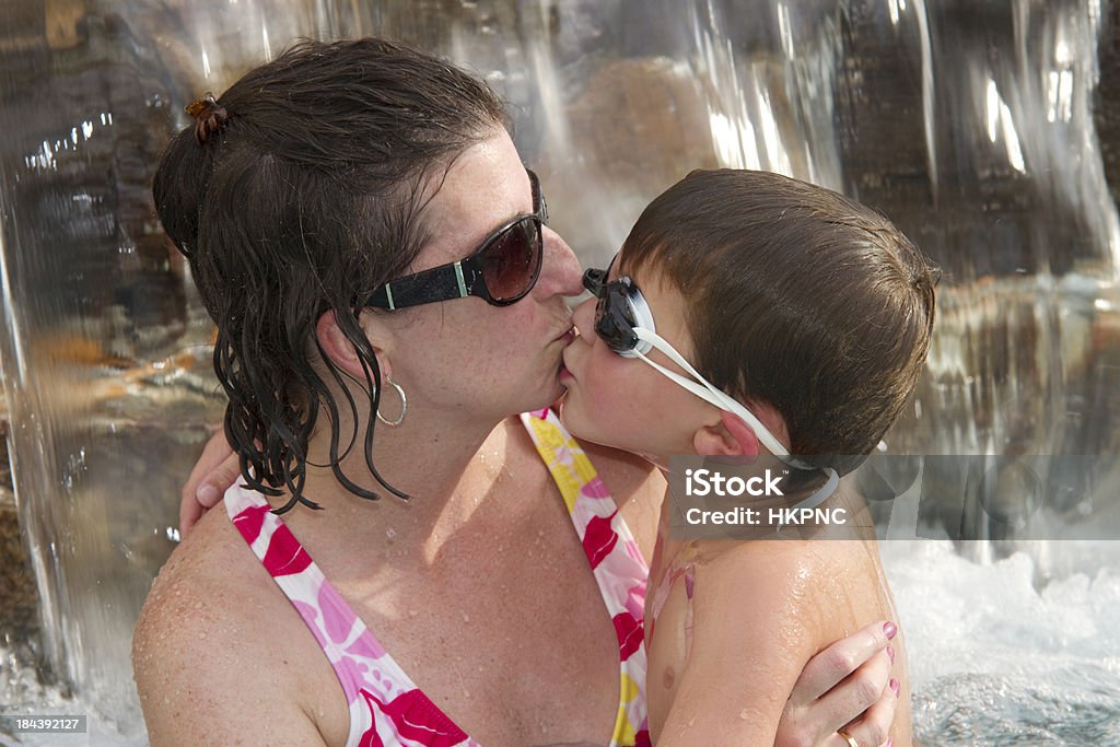Garçon Embrasser sa mère dans la piscine et le bain à remous avec cascade - Photo de 4-5 ans libre de droits
