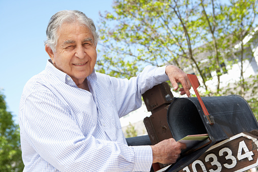 Senior Hispanic Man Checking Mailbox Smiling at Camera
