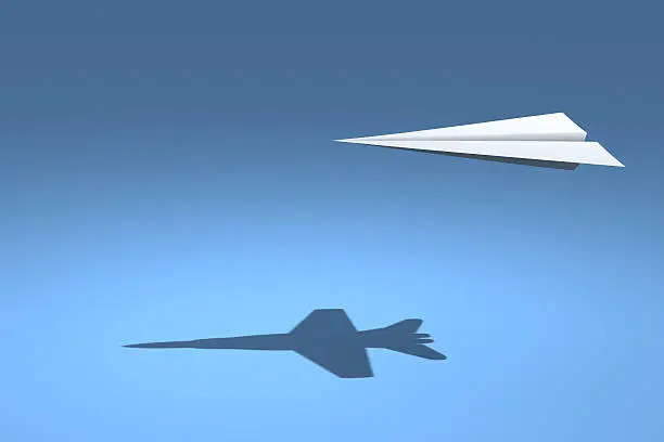 A paper plane flies casting shadows of fighter jet.