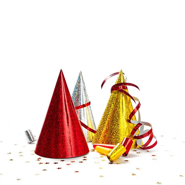 Party decorations: hats, whistles, streamers, confetti on white background. Square composition, copy space, studio shot.