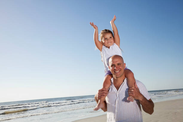 istock Father with little girl on shoulders at beach 184393625