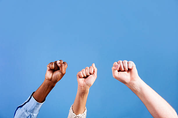 istock Three clenched fists punch the air against blue background 184394595