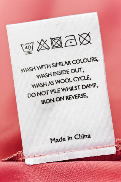 Clothes label of item made in China Close-up of a label on a pink cotton garment giving cleaning instructions. There is a companion image: garment stock pictures, royalty-free photos & images